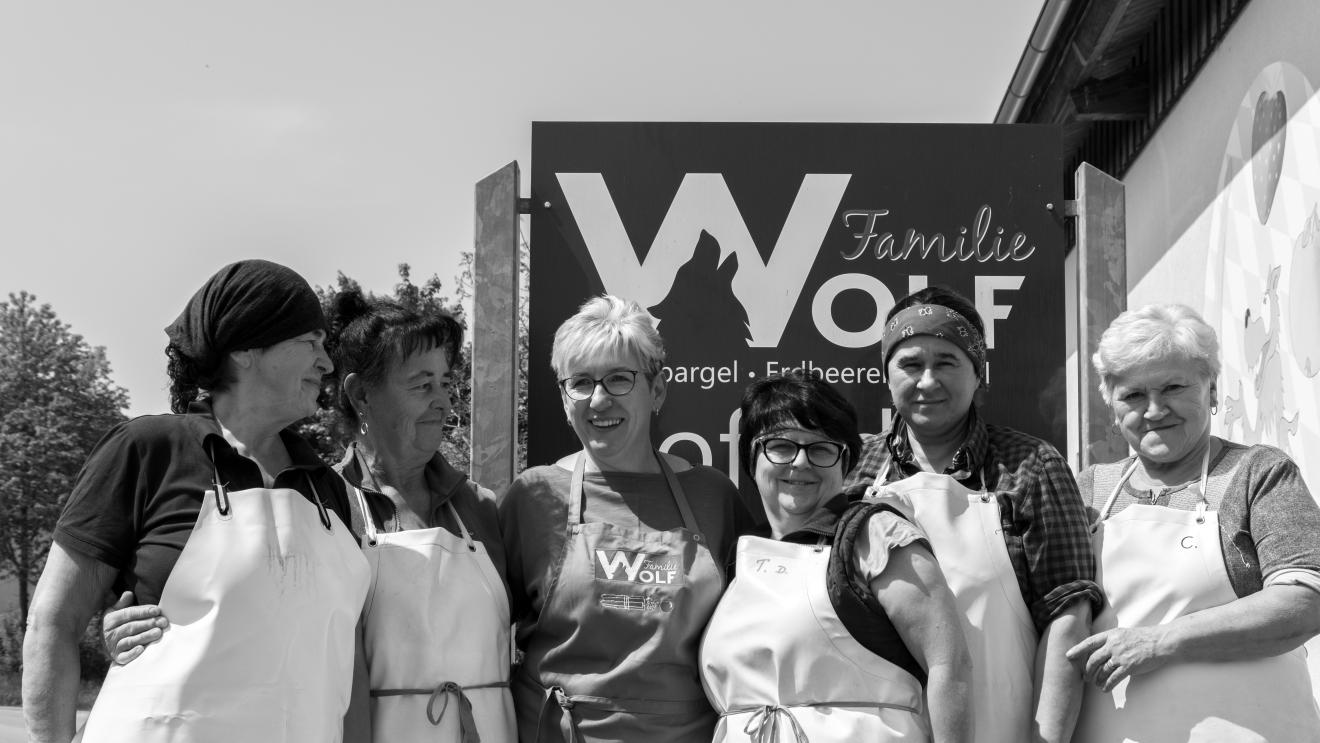 Wolf (dritte Person von links) mit ihren Saisonarbeiterinnen vor dem Betriebsschild. 