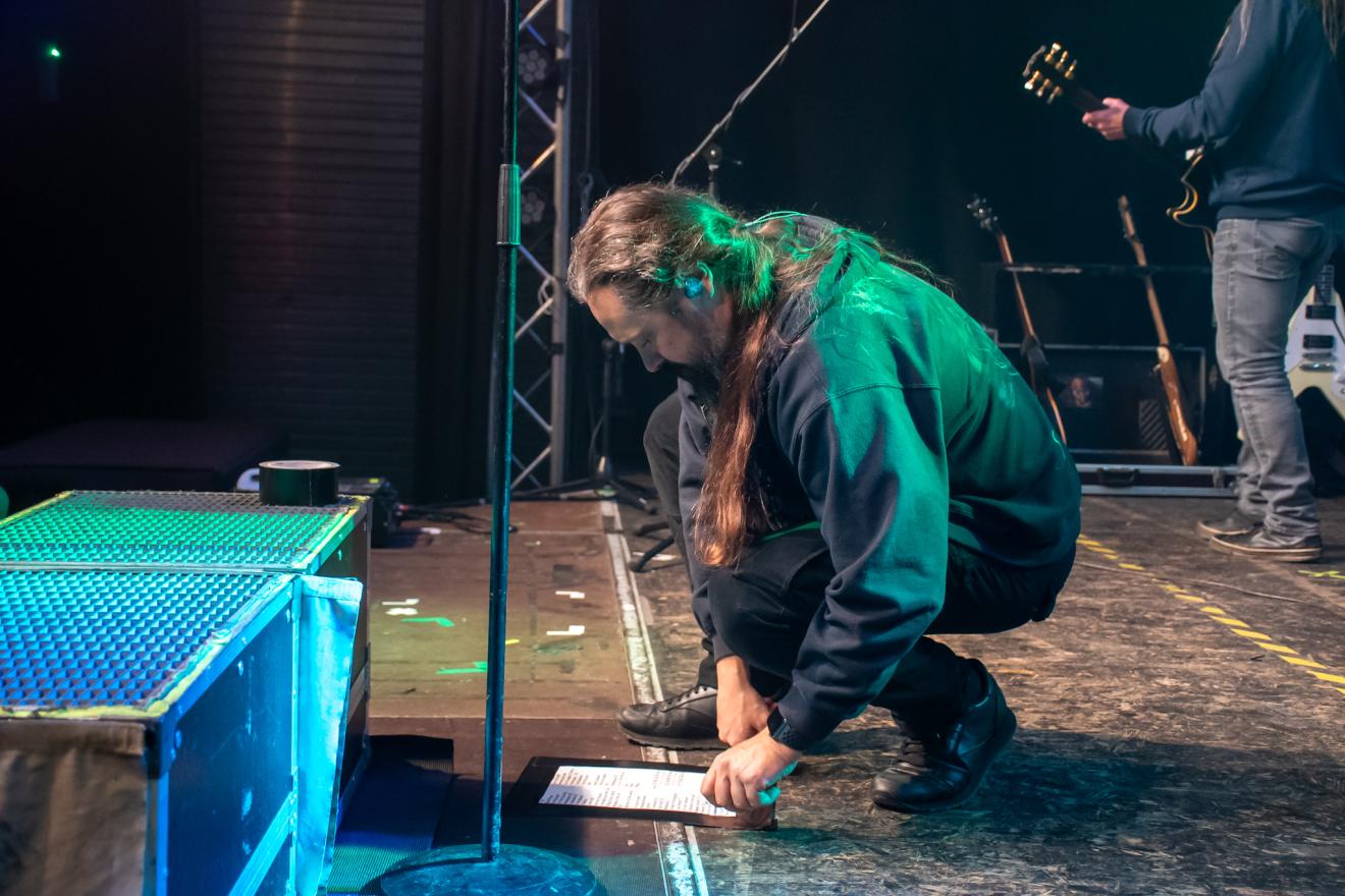 Daniel bereitet einige Setlists auf der Bühne vor.