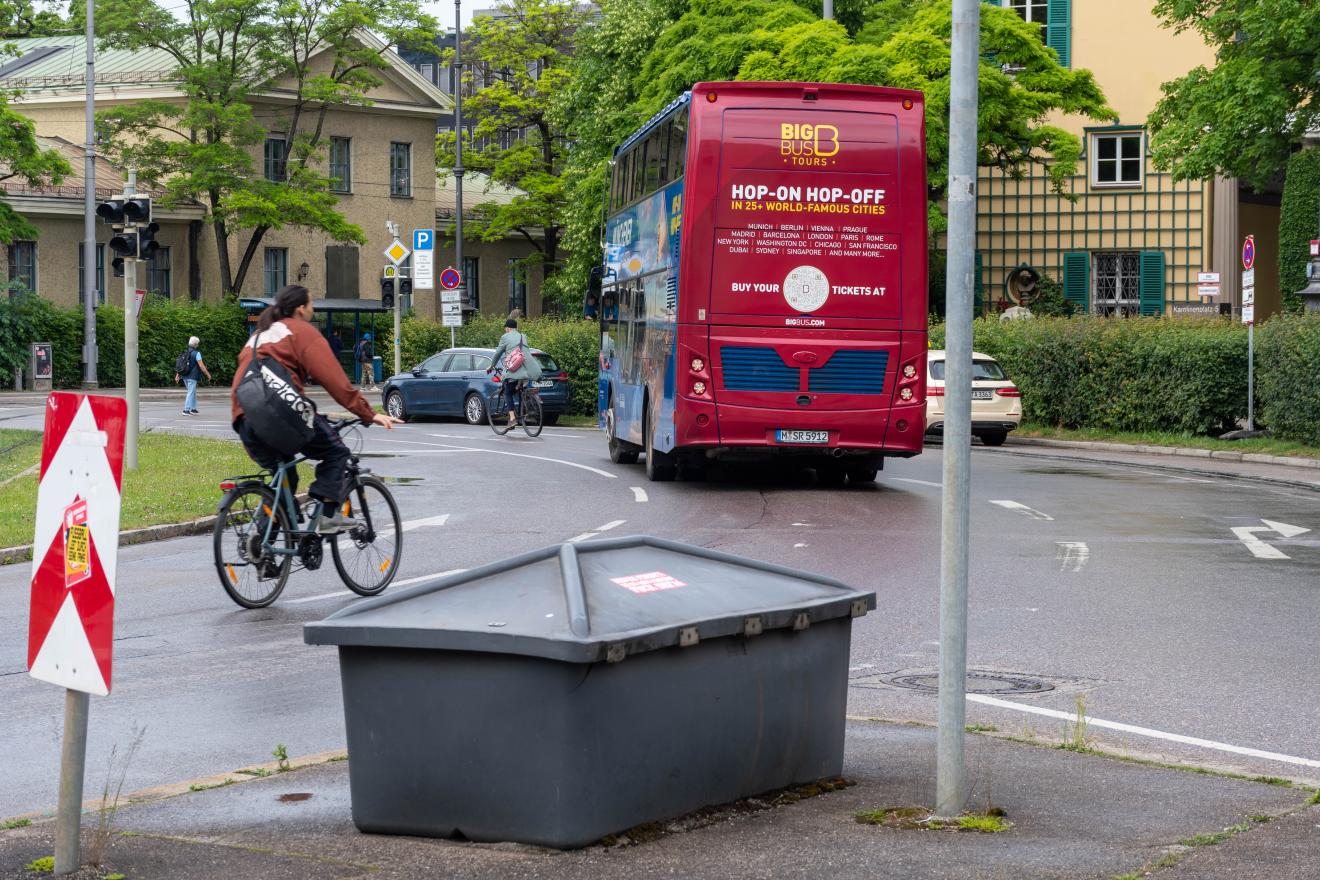 Radfahrer und Bus müssen zusammen in einem Kreisverkehr fahren.