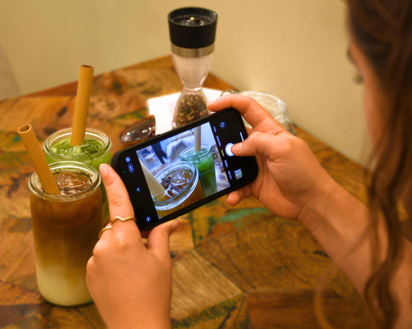 Ein Mädchen, was ein Foto von ihren Getränken macht.