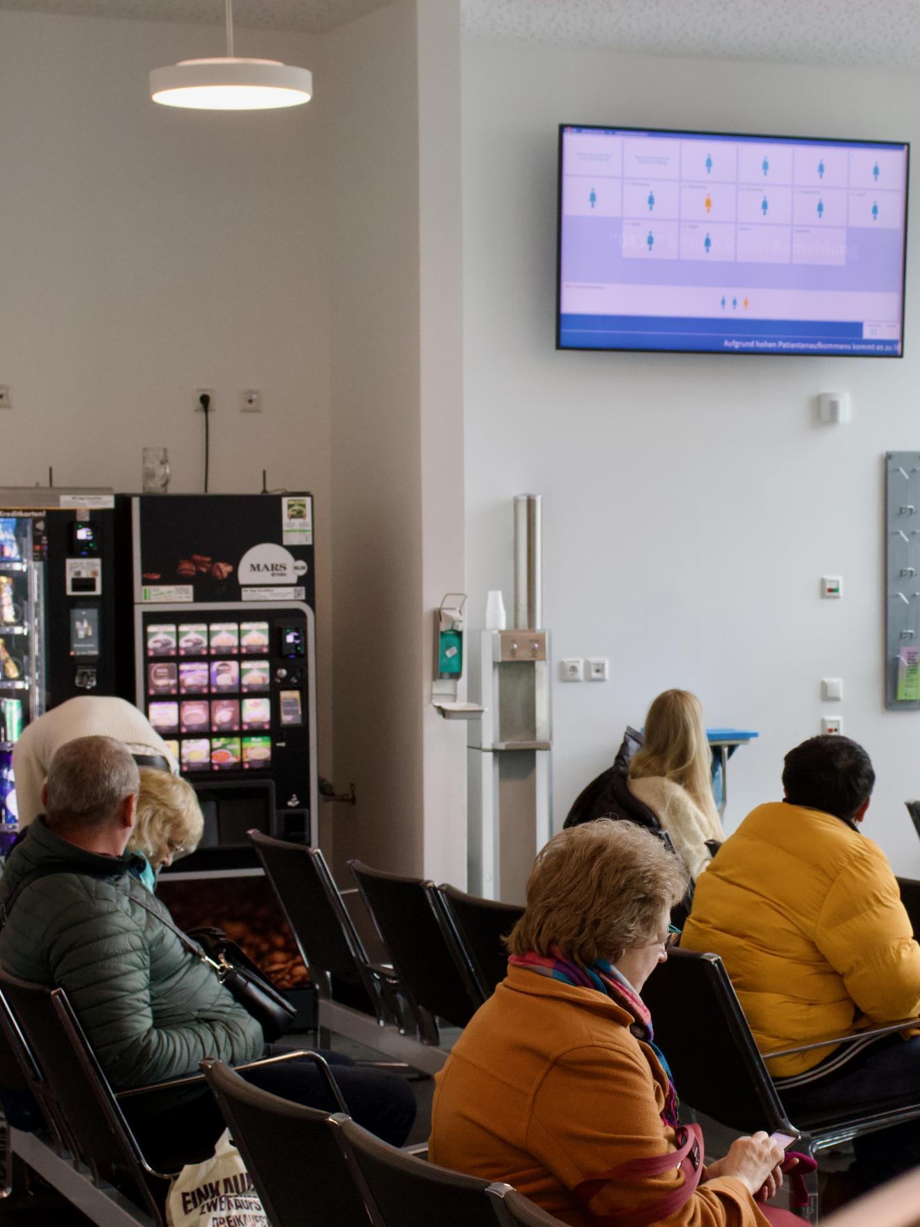 Der Warteraum der Notaufnahme, zu sehen sind 5 Personen unterschiedlichen Alters und Herkunft