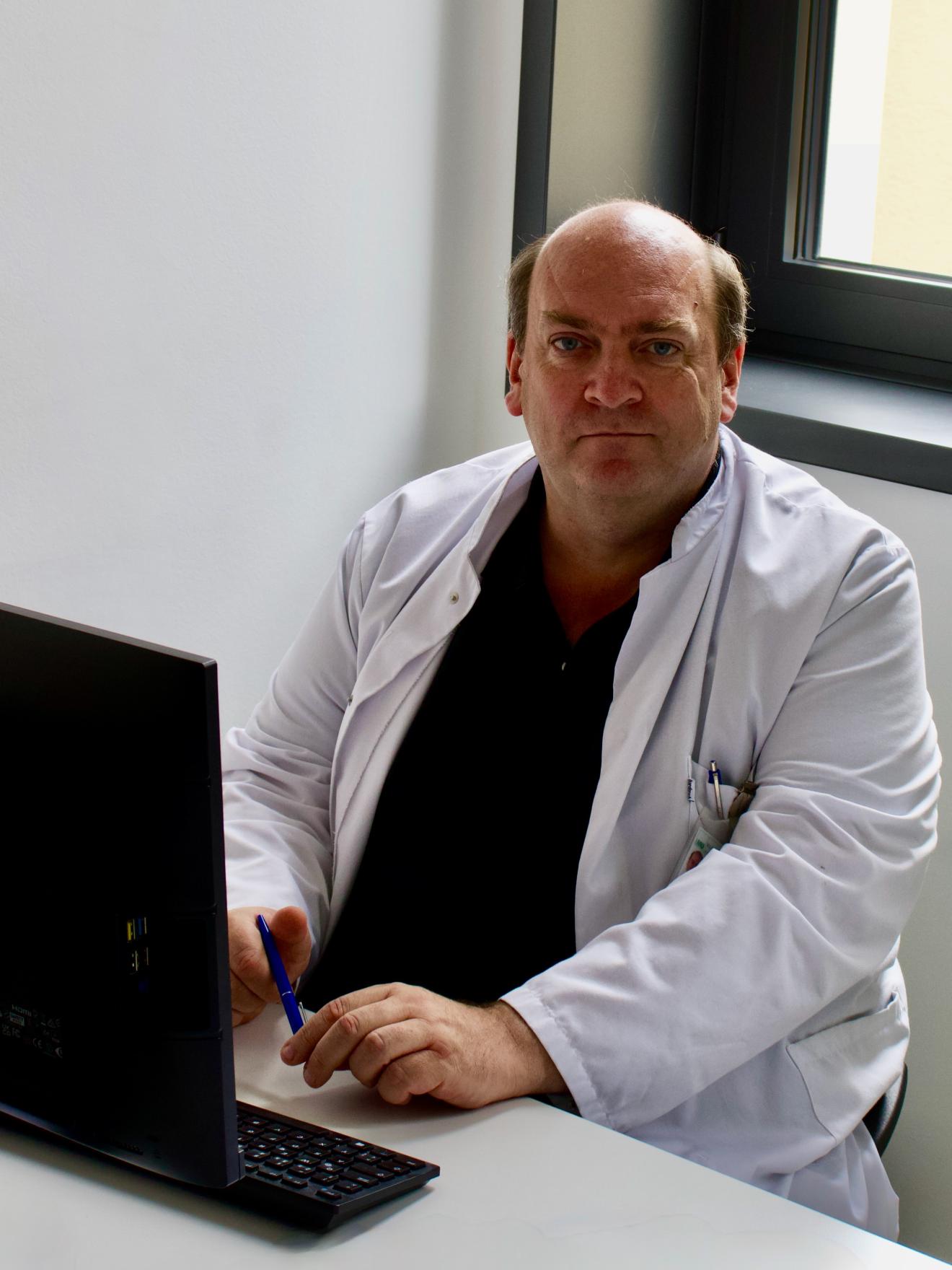 Prof. Wörnle an seinem Arbeitsplatz wie er in die Kamera blickt