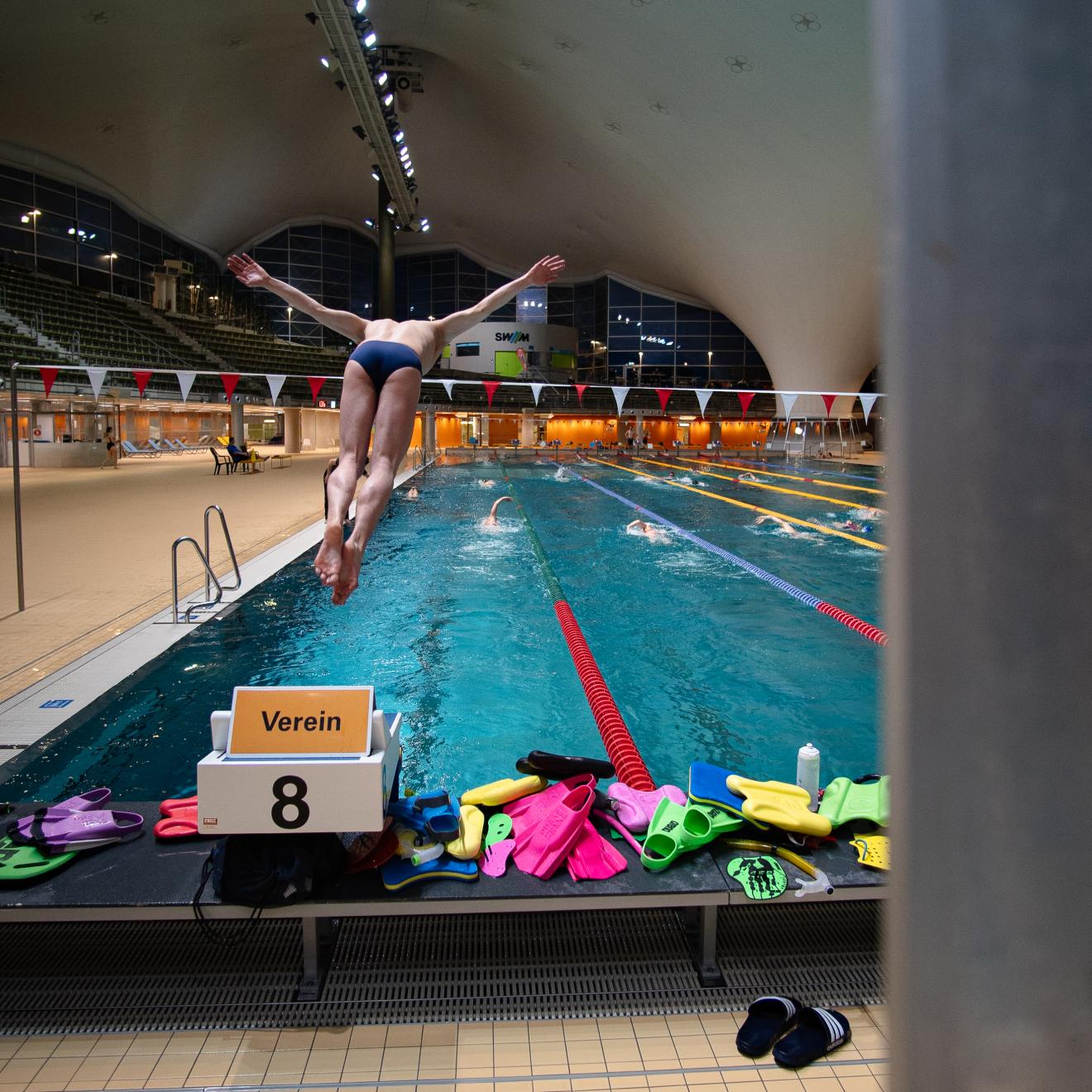 Ein Schwimmer springt vom Startblock ins Wasser.