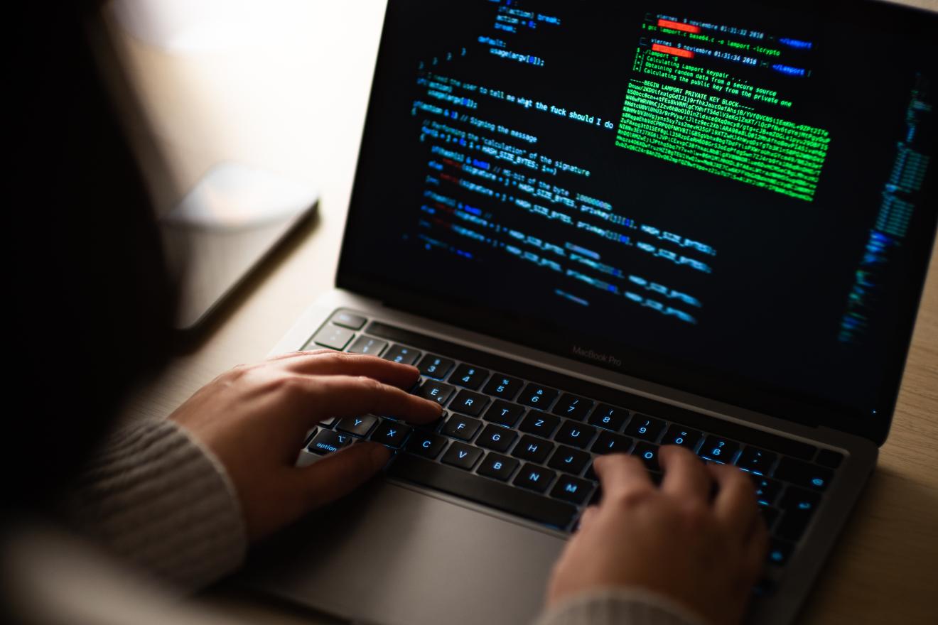 Eine Person sitzt am Computer, verschiedene Codes sind geöffnet