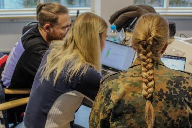Zwei Studentinnen und ein Student lernen gemeinsam am Laptop