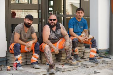 3 Bauarbeiter auf der Baustelle machen Mittagspause 