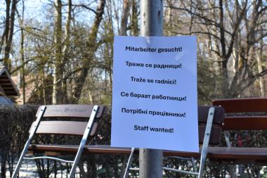 Symbolbild - leerer Biergarten und ein Schild mit "Mitarbeiter gesucht" in verschiedenen Sprachen