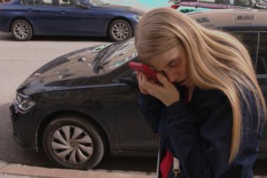 Kerstin Mirschberger steht auf einem Bürgersteig und hält sich das Handy direkt vor ihr Auge um etwas erkennen zu können.