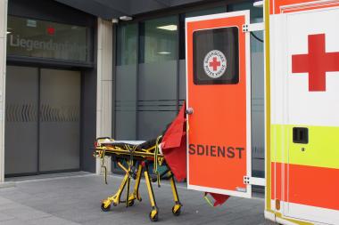 Eine Trage steht zwischen Rettungswagen und der Liegendanfahrt der Notaufnahme 