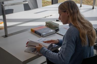 Studentin sitzt am Schreibtisch vor einem BWL Buch