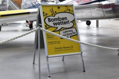 Das Plakat zur Ausstellung „Bombenwetter“ lädt Alt und Jung ein, sich über die Herkunft vieler Redewendungen zu informieren – oft sind es Dinge, die man so vorher nicht auf dem Schirm hatte.