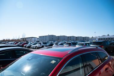 Man sieht einen Parkplatz voll mit Autos, im Hintergrund die Wohngebäude der Universität der Bundeswehr.