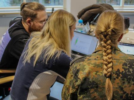 Zwei Studentinnen und ein Student lernen gemeinsam am Laptop