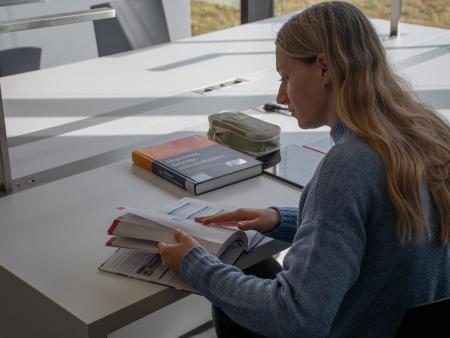 Studentin sitzt am Schreibtisch vor einem BWL Buch